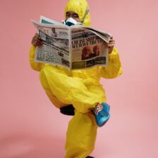 man in yellow protective suit holding a newspaper